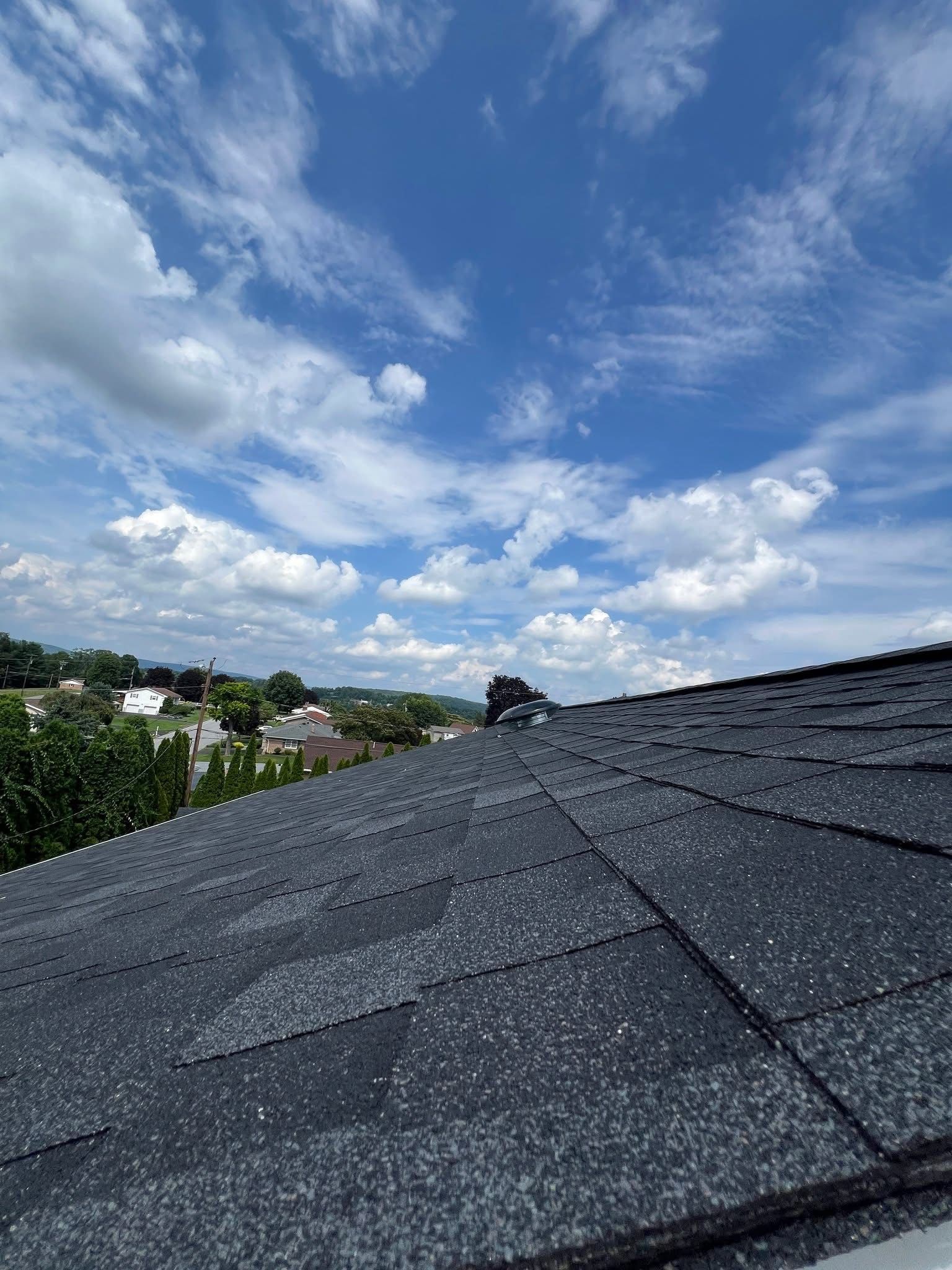 Dark rooftop with a blue sky and fluffy clouds in the background.