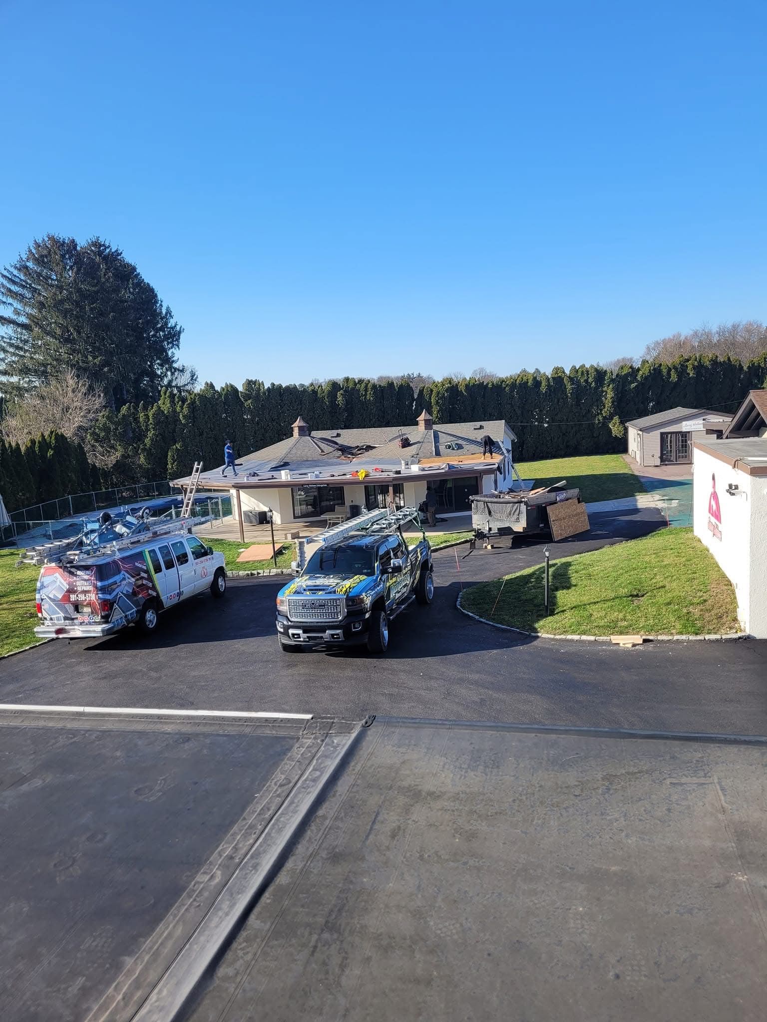 Vehicles and equipment at a house under construction; blue sky overhead.