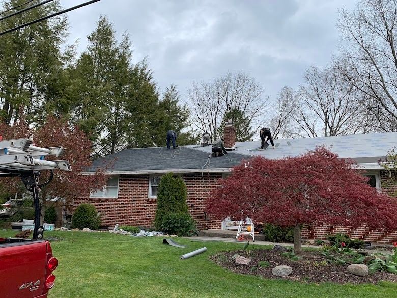 Three roofers working on a house roof on a cloudy day.