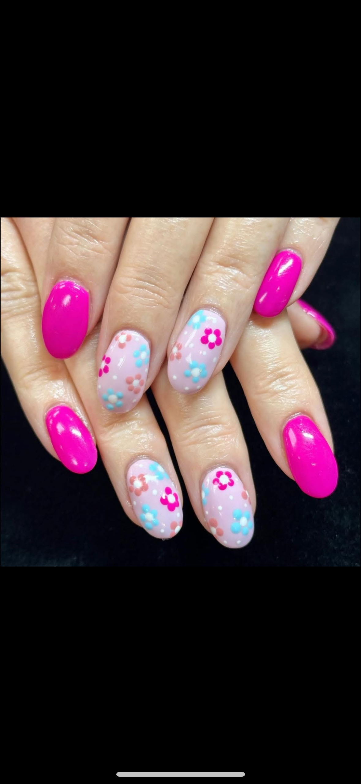 A close up of a woman 's nails with pink and white flowers on them.