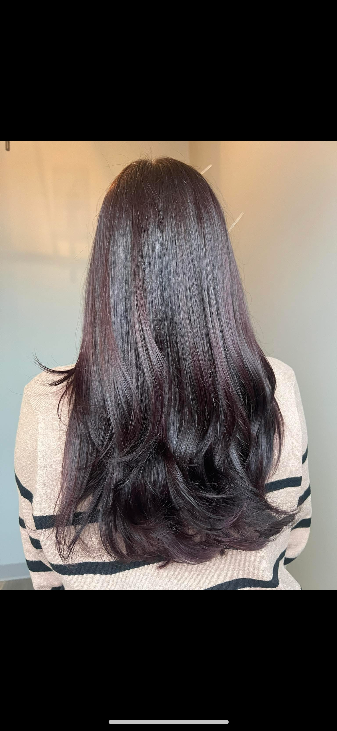 A woman with long dark hair is wearing a striped sweater.