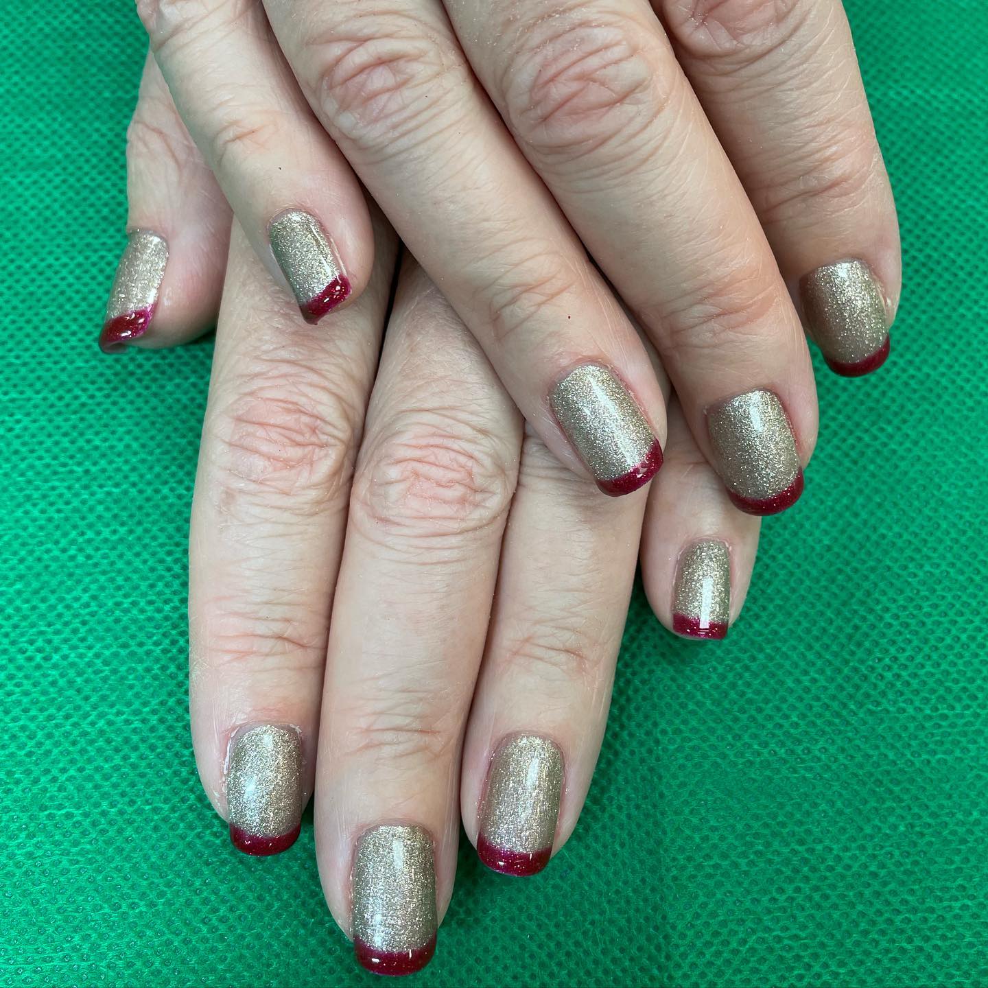 A close up of a woman 's nails with gold and red polish