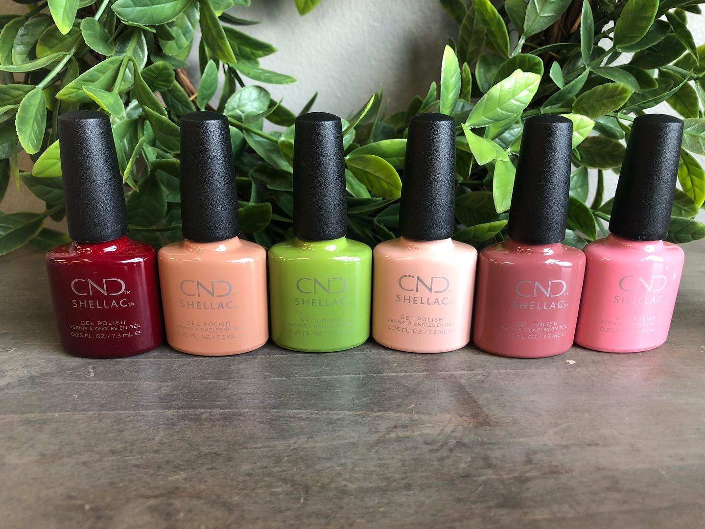 Six bottles of nail polish are lined up in a row on a table.
