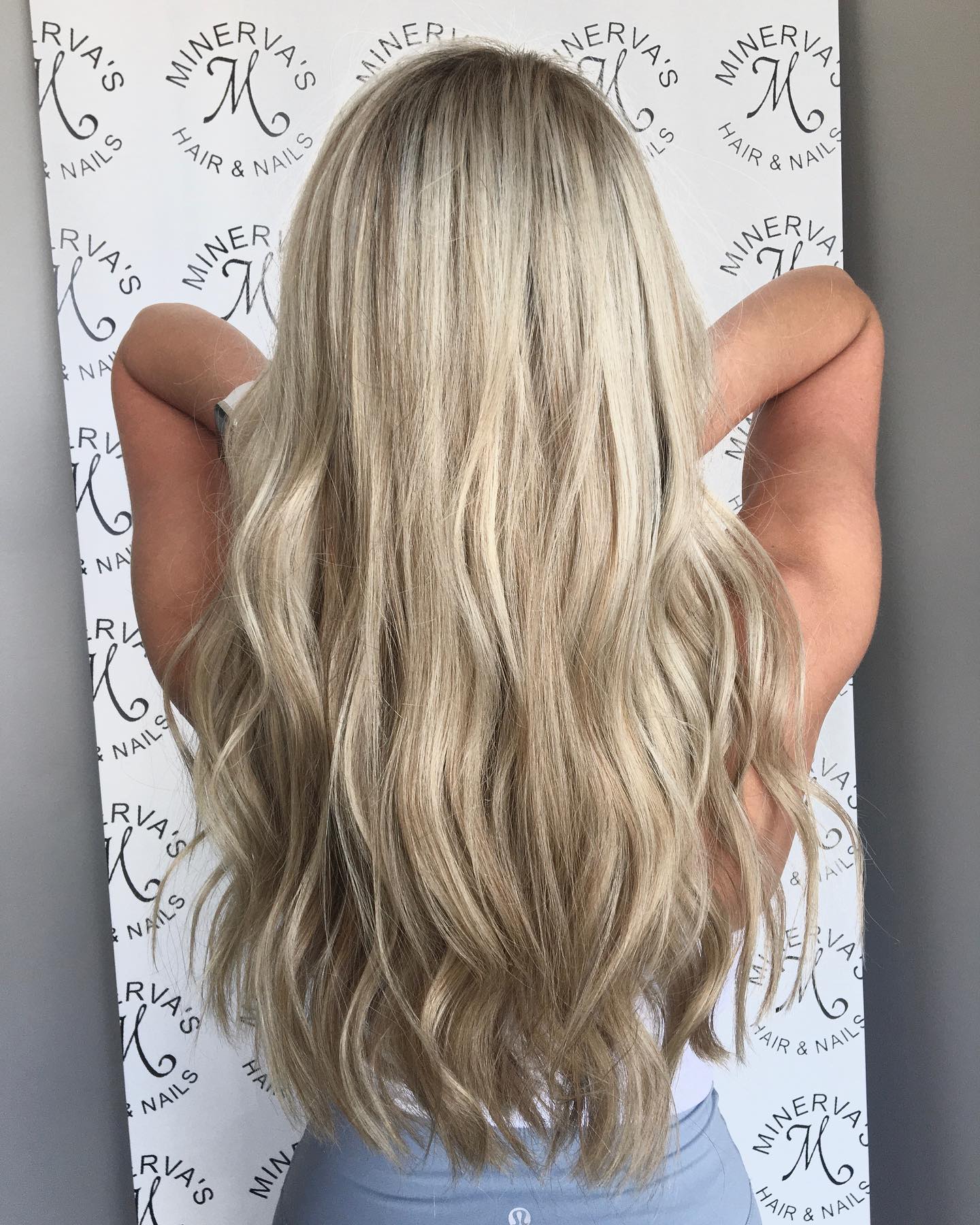 A woman with long blonde hair is standing in front of a sign that says minerals