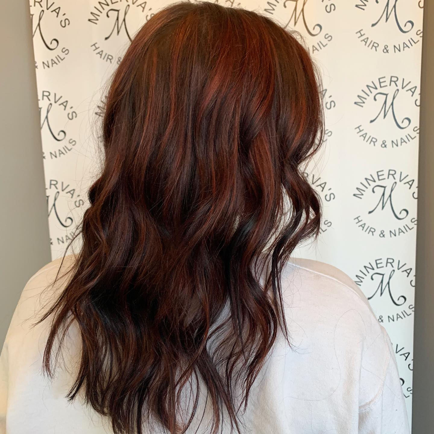 A woman is standing in front of a sign that says minerva 's hair & nails