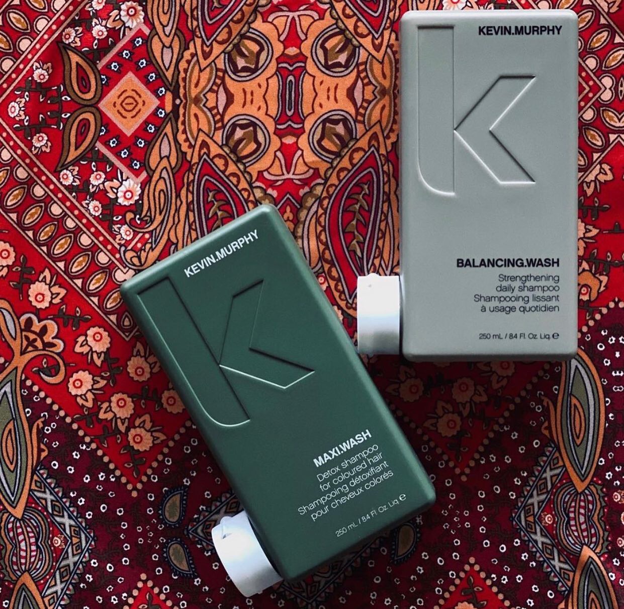 Two bottles of kevin murphy hair products are sitting on a paisley cloth