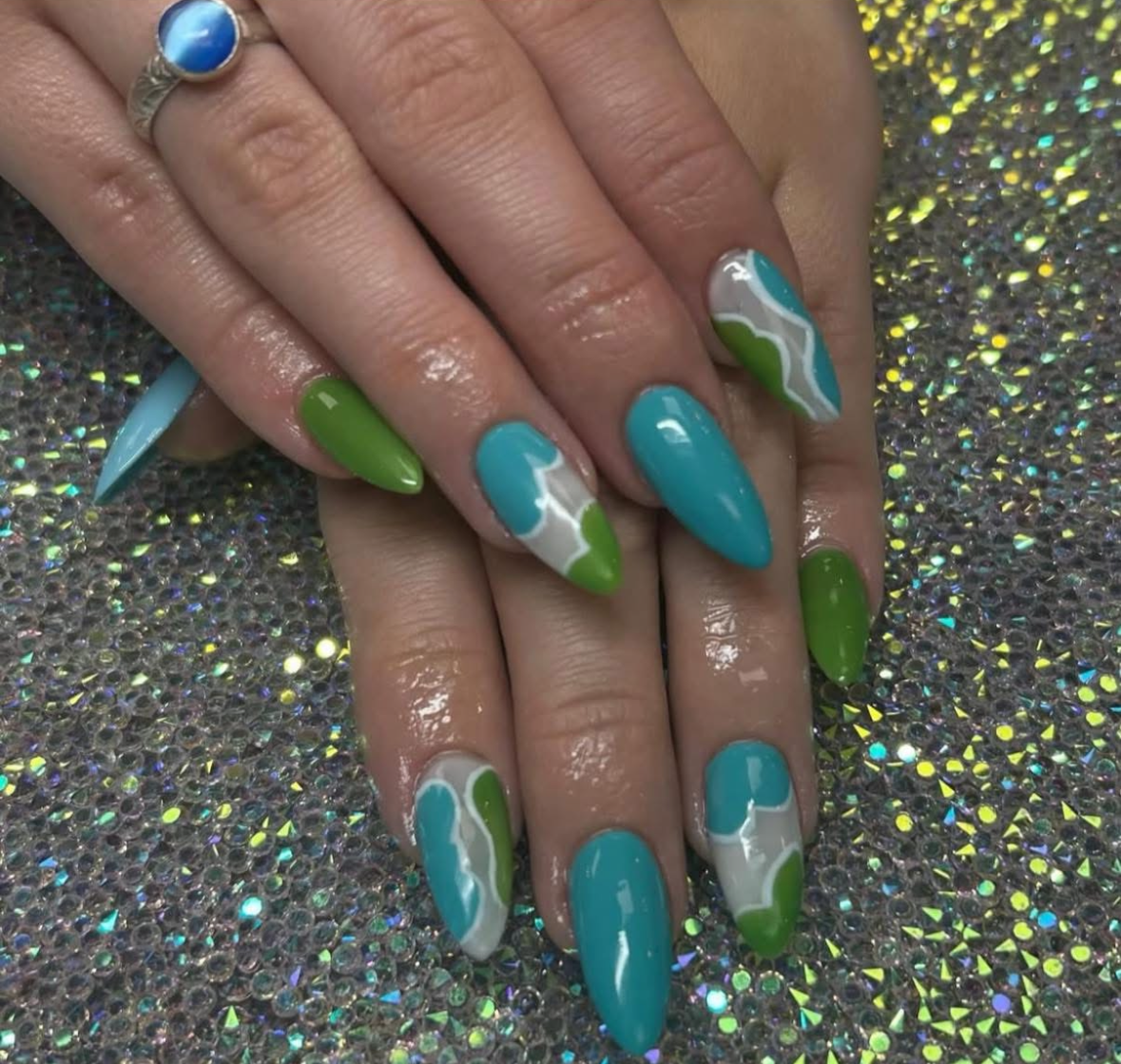 A woman with long wavy blonde hair is wearing a blue sweater.