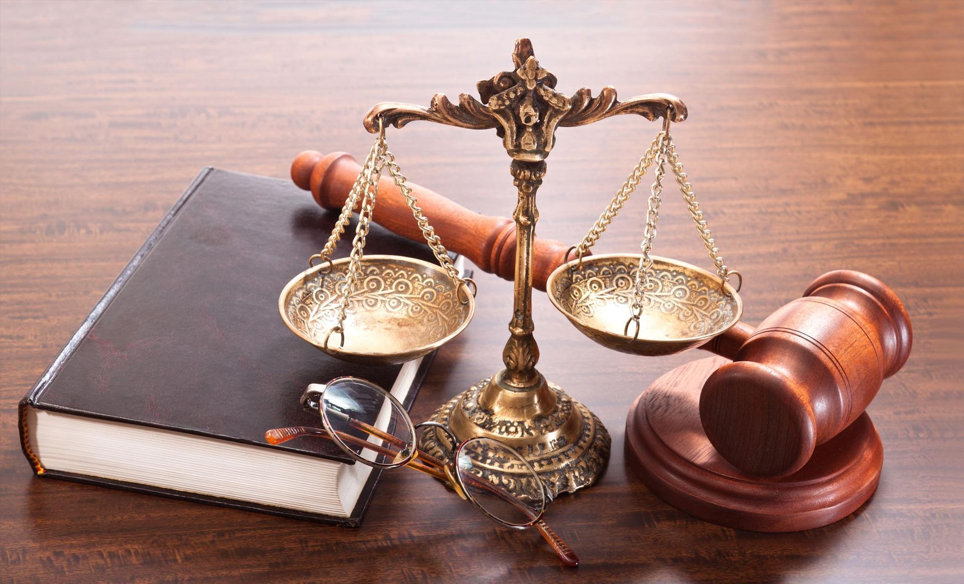 A wooden gavel a scale and a book on a wooden table