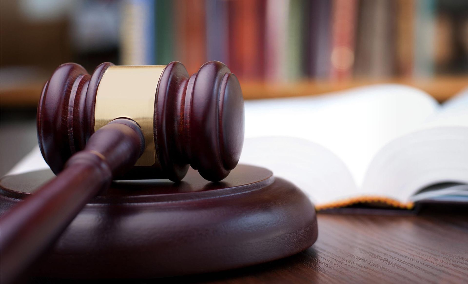 A wooden judge 's gavel is sitting on a wooden table next to an open book.