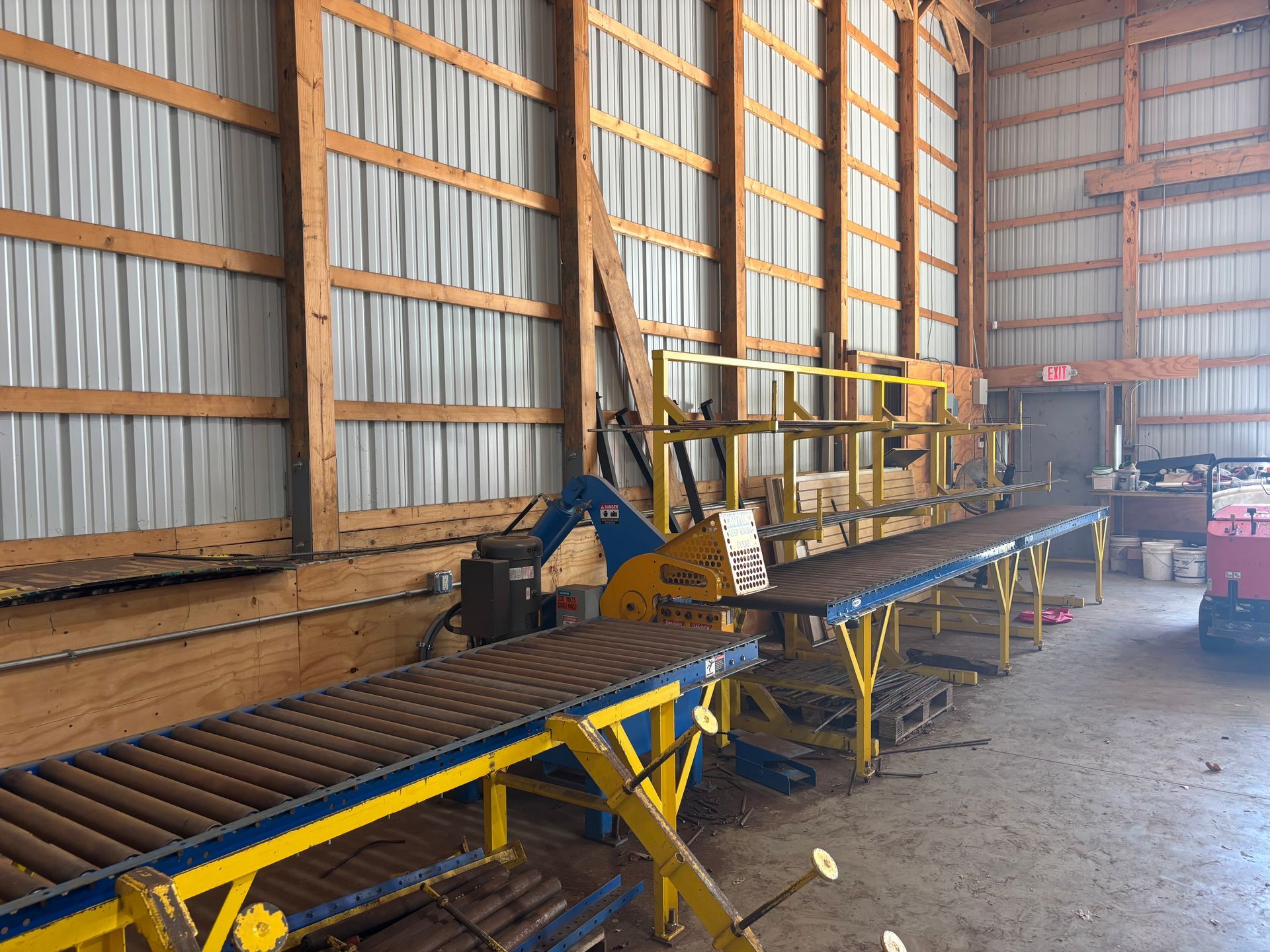 Long conveyor belt inside a barn-like industrial shed with metal walls and wooden support beams