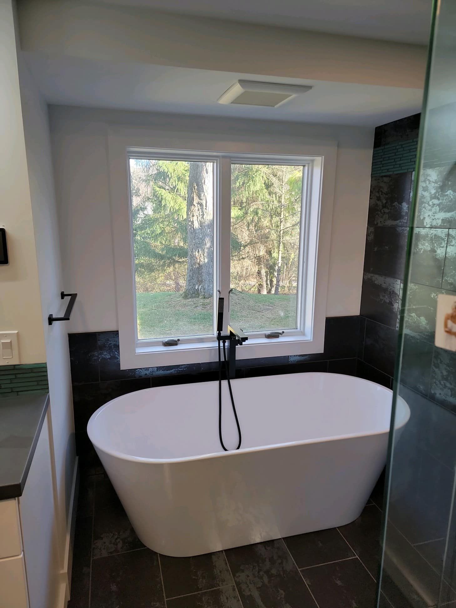 Modern bathroom with a freestanding tub and large window overlooking trees