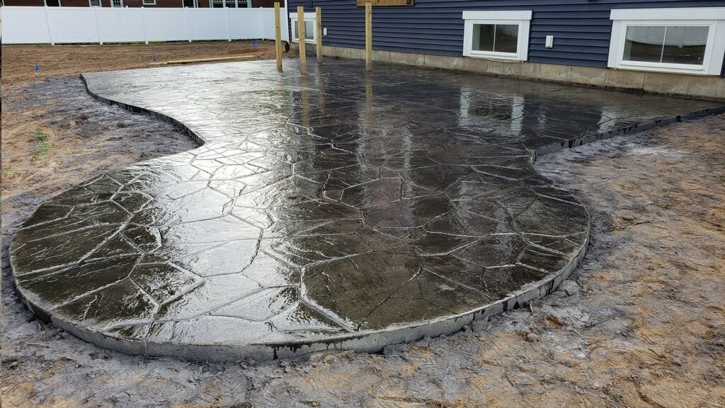 Rainwater collecting in a muddy yard, forming a large reflective puddle near a building.