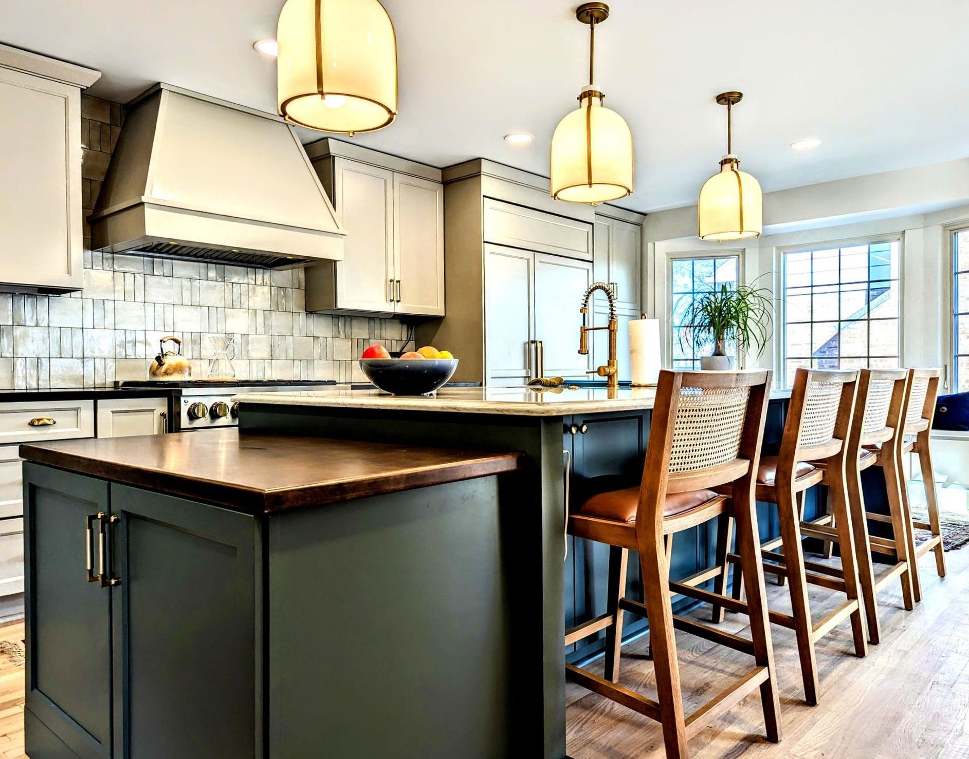 Modern kitchen with dark island, light cabinets, pendant lights, and breakfast bar stools