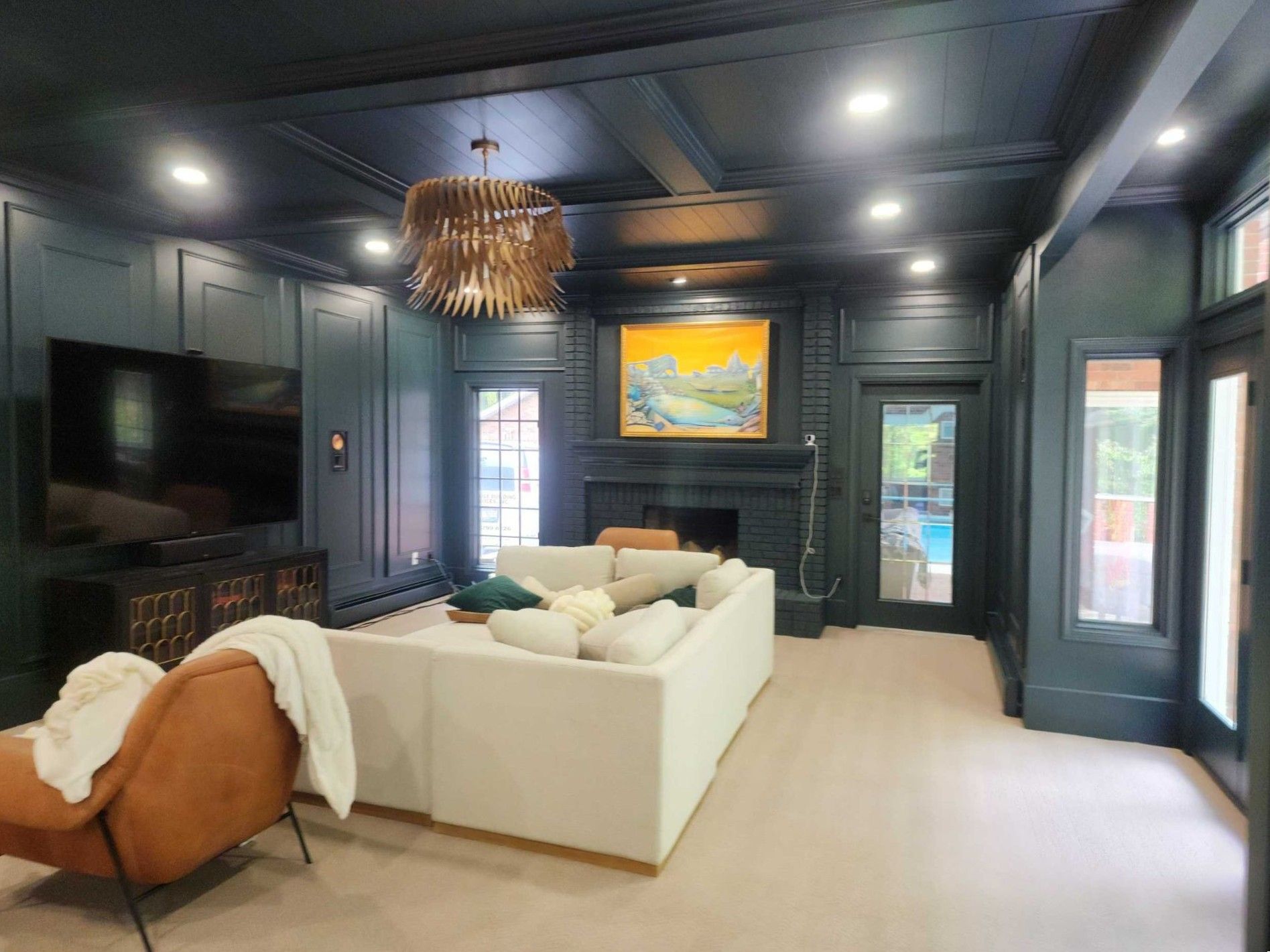 Modern living room with dark walls, white sofa, fireplace, and large TV