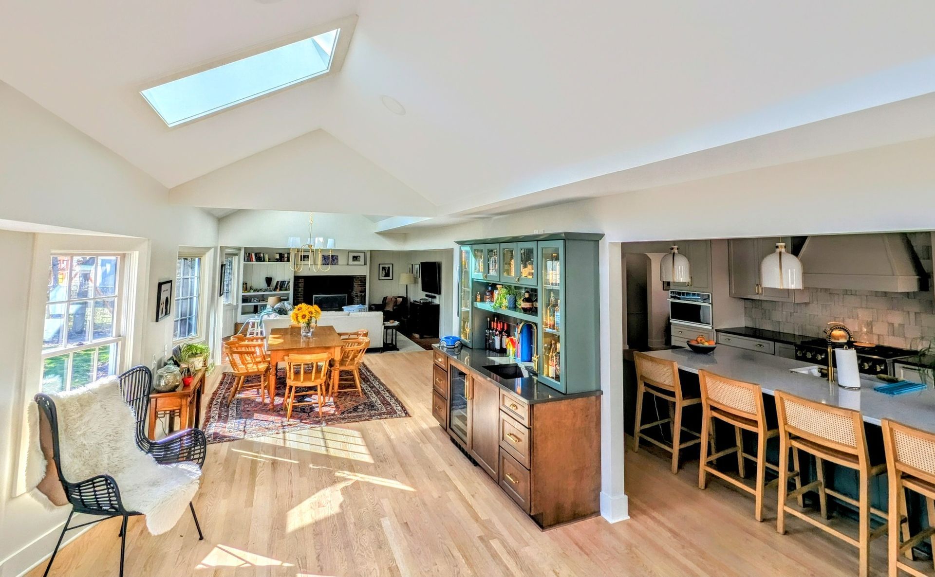 Bright open-plan kitchen and dining room with skylights, wood floors, and bar seating