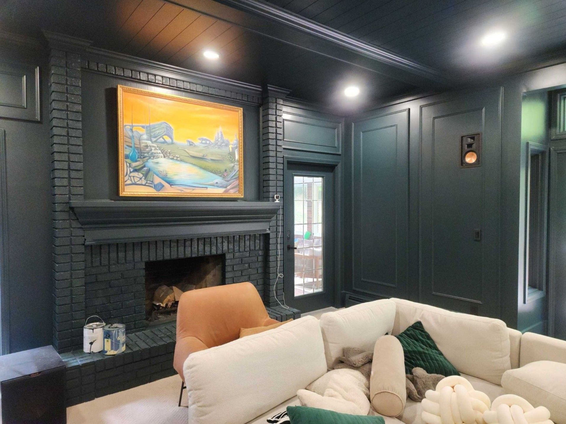 Elegant living room with dark paneled walls, fireplace, colorful painting, and a beige sofa in the foreground