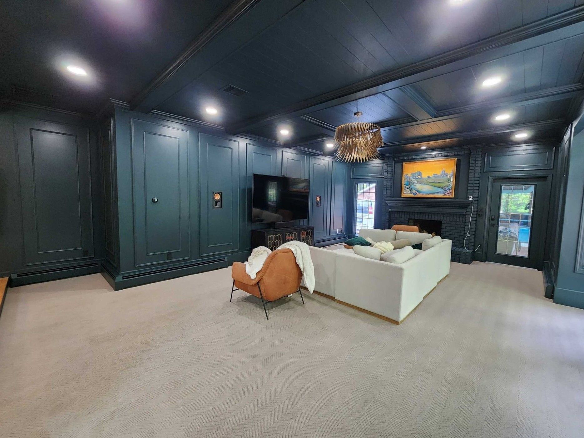 Modern living room with dark walls, white sofa, orange chair, and a TV on the far wall.