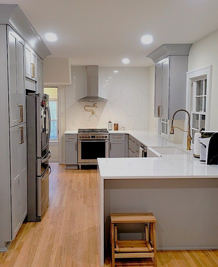 Bright modern kitchen with white cabinets, stainless fridge, island, and wood floor