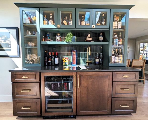Dark wood bar cabinet with shelves, glass doors, and bottles in a living room