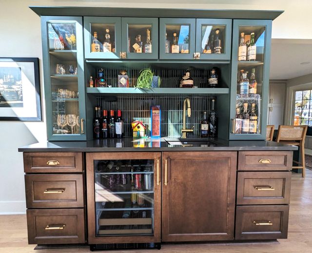 Dark wood bar cabinet with shelves, glass doors, and bottles in a living room