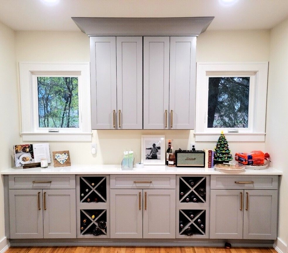 Built-in kitchen cabinets with gray lower drawers, white upper cabinets, windows, and holiday decor on the counter