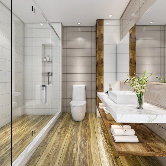 Modern bathroom with glass shower, white toilet, floating sink, and wood-look floor.