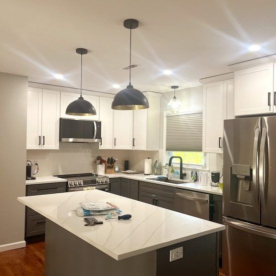Modern kitchen with white cabinets, stainless steel appliances, island, and pendant lights