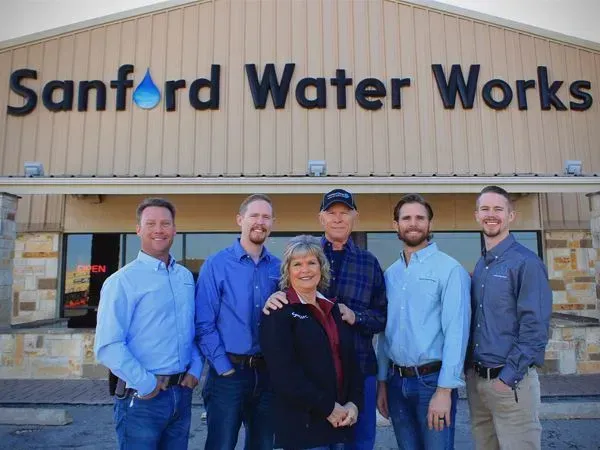 People standing in front of the Sanford Water Works building; business team smiling, group photo.