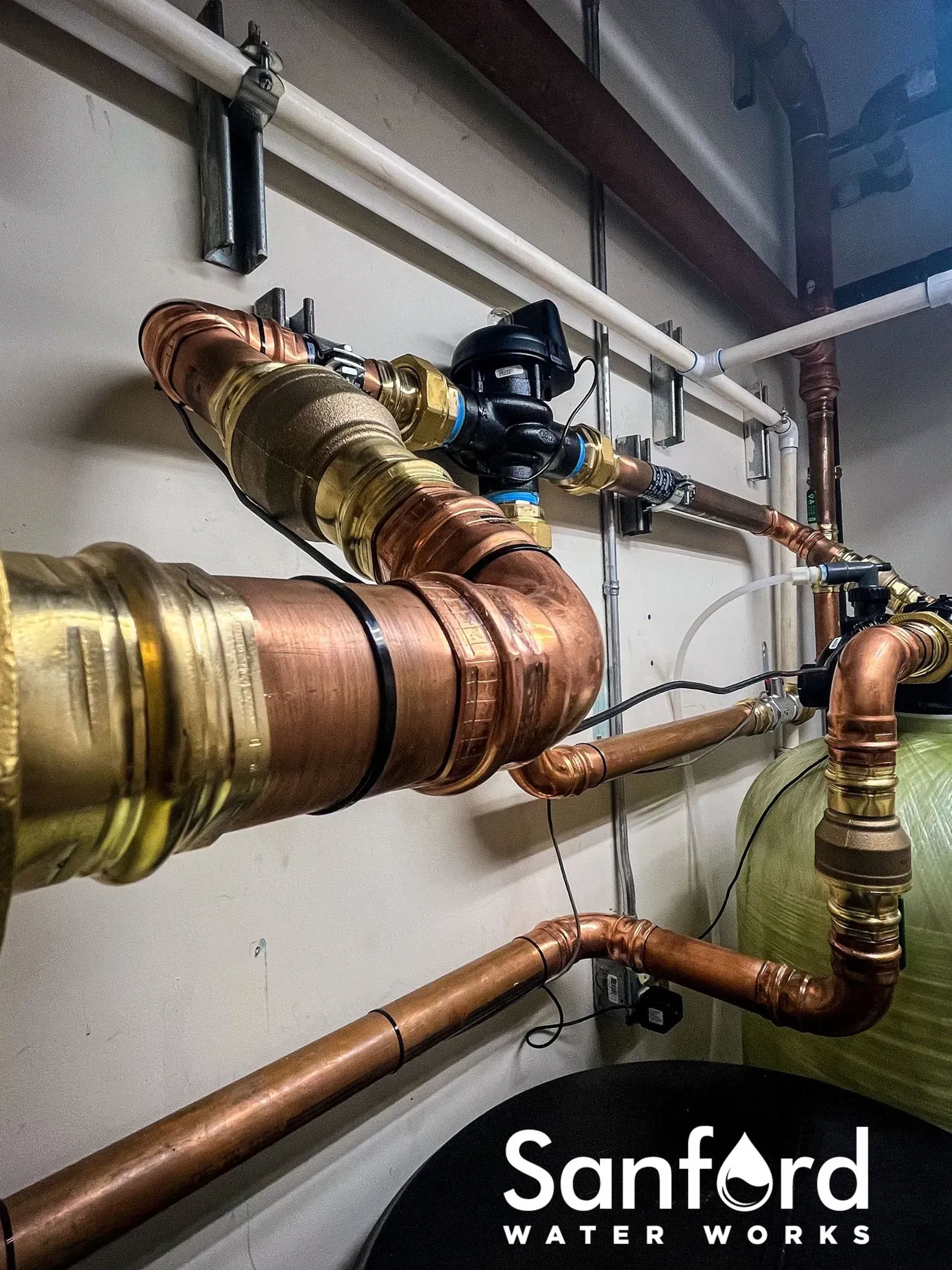 Copper water pipes, valves, and fittings installed against a neutral wall; 