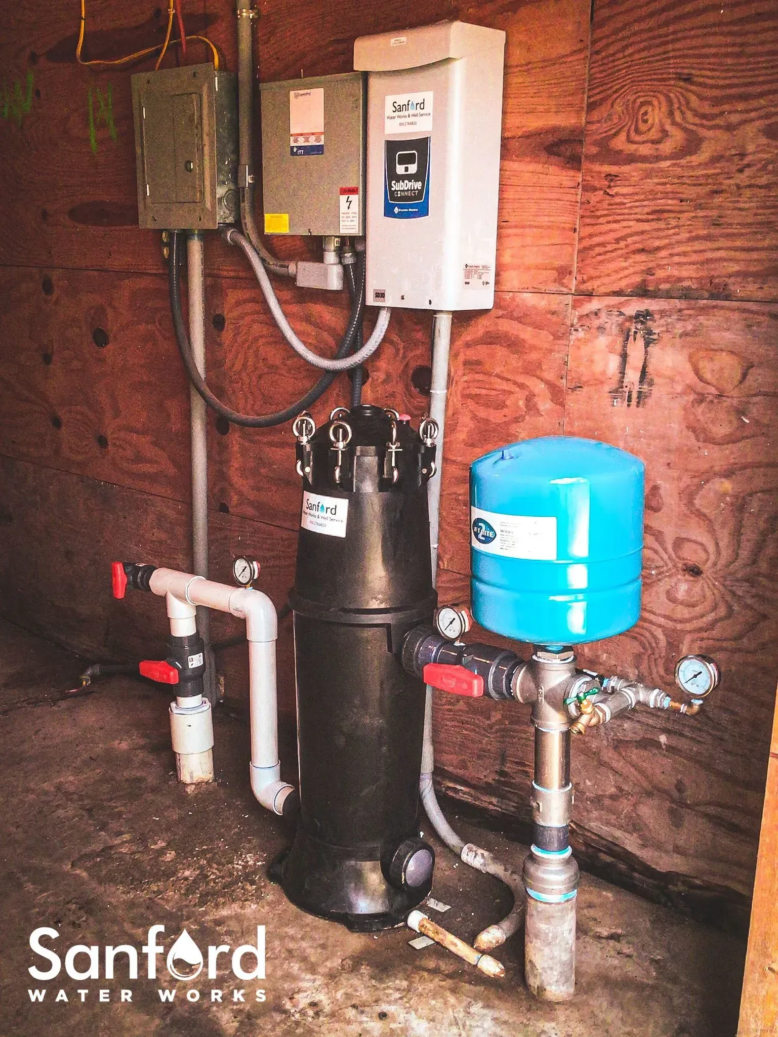 Well water system components in a wooden enclosure. Includes tank, filter, and electrical boxes.