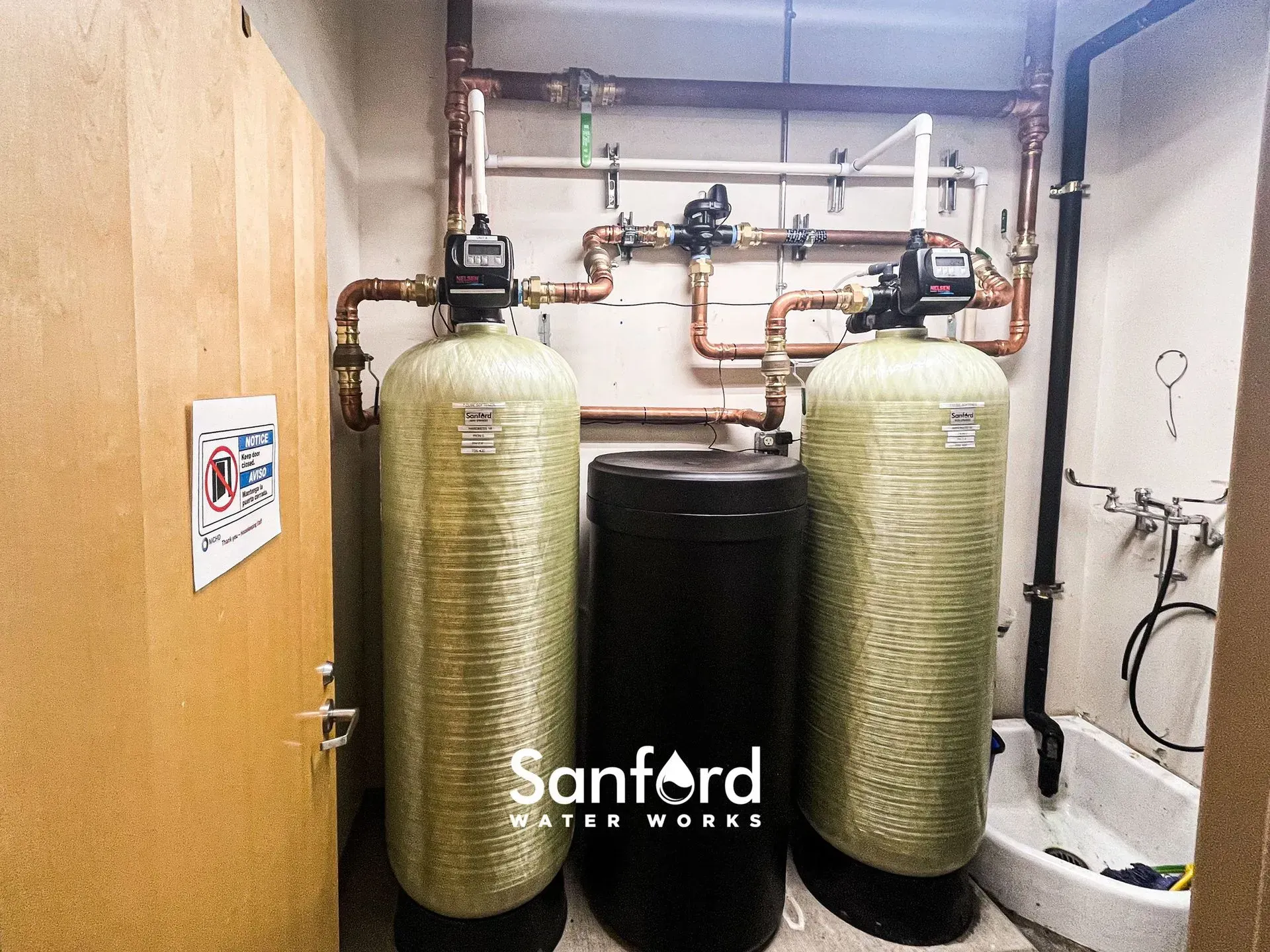 Water filtration system with copper pipes and two cylindrical tanks, and a black tank.