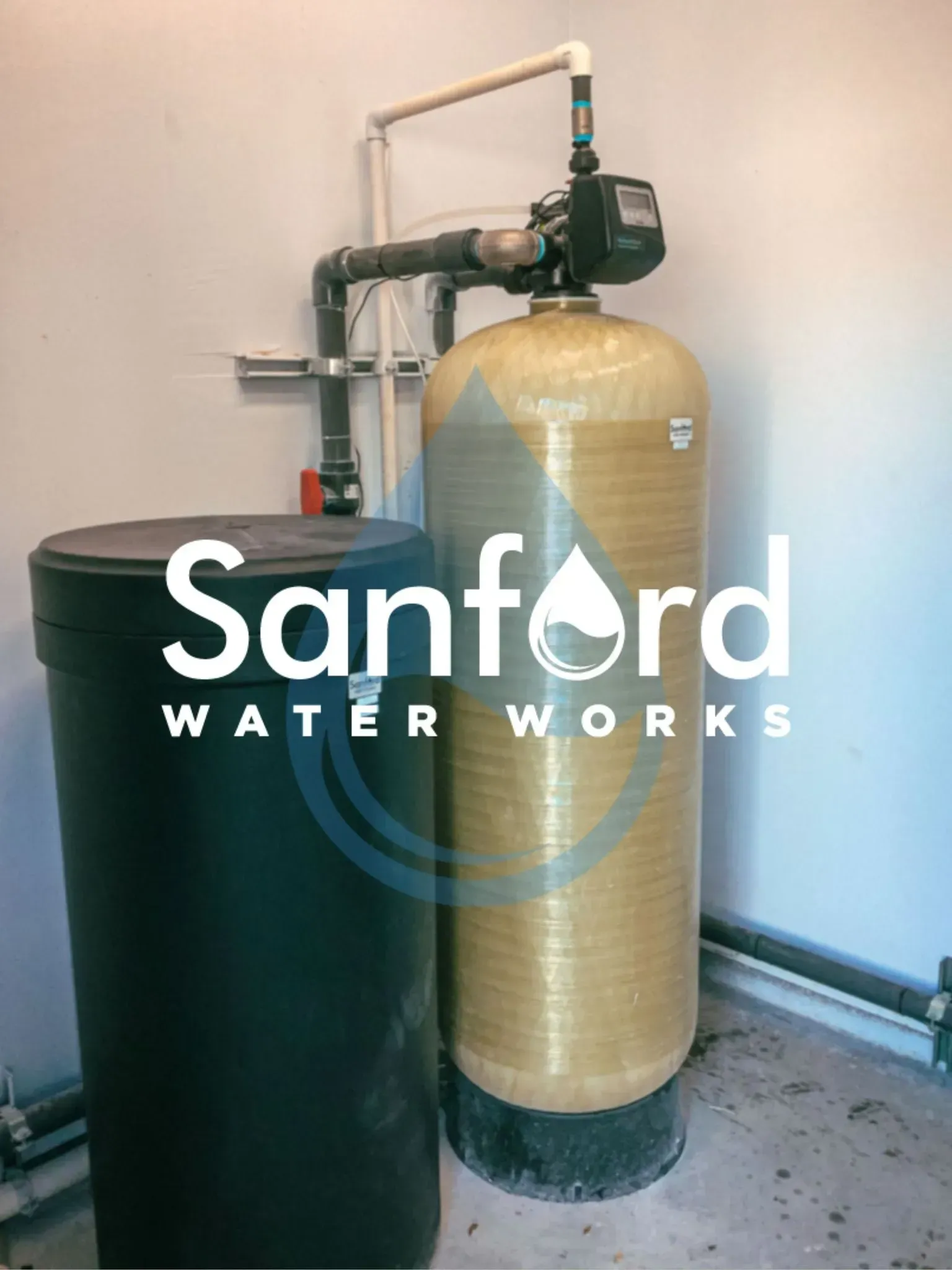 Water filtration system with black tank and tall yellow tank, installed near a wall.