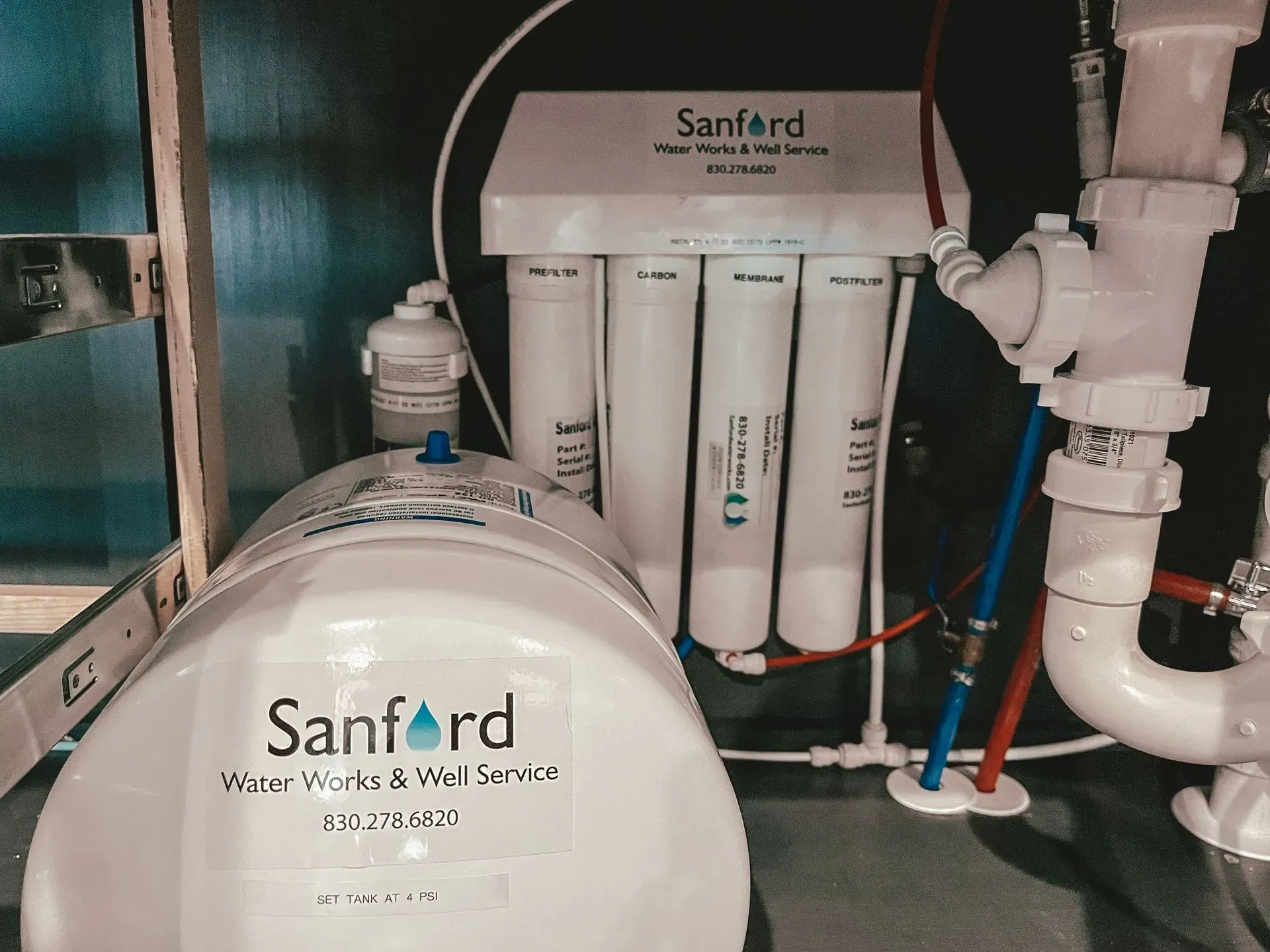 Sanford water filtration system under a sink, with filter cartridges and storage tank.