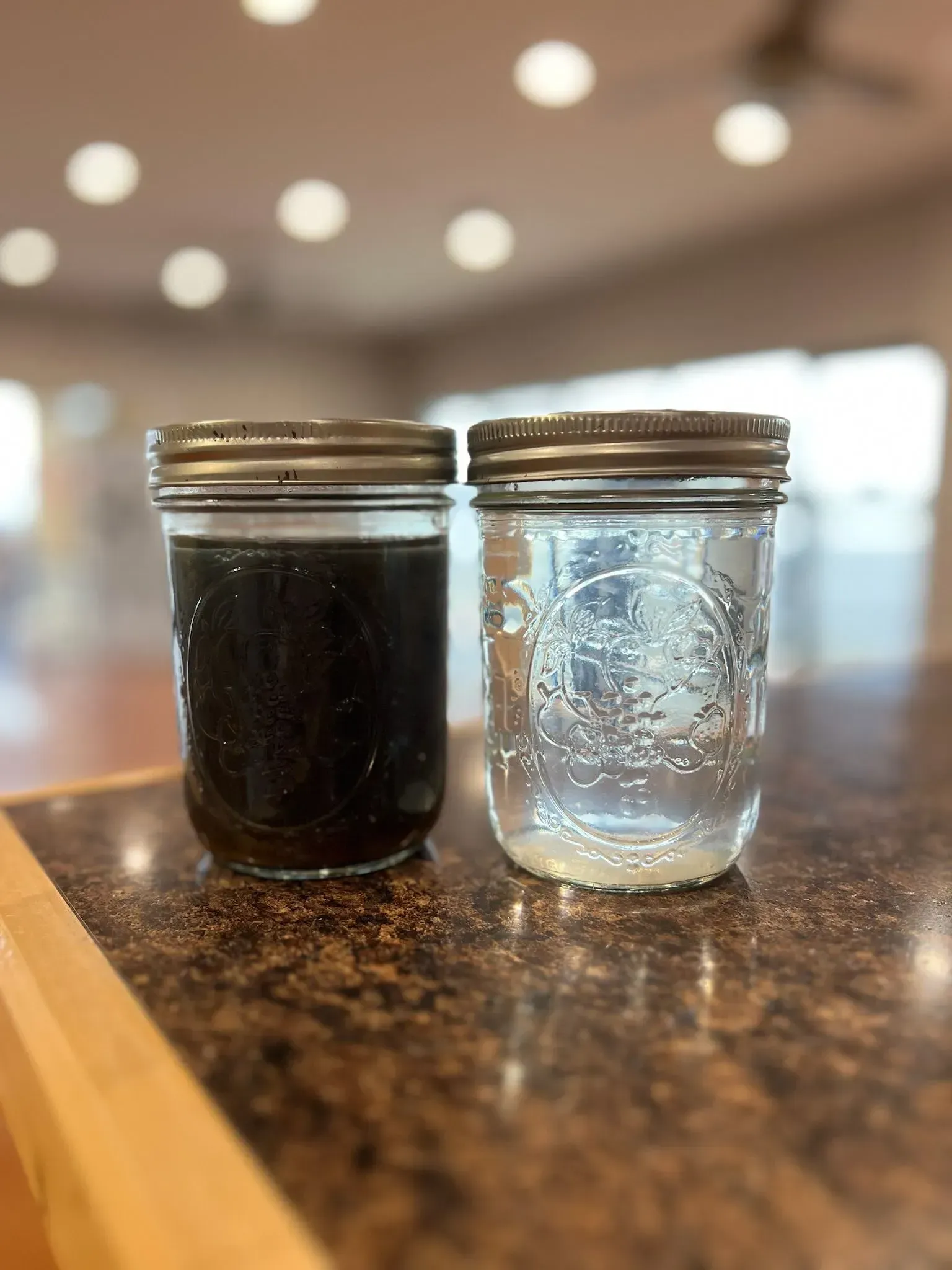 Two mason jars: one with dark liquid, the other with clear liquid, on a countertop.