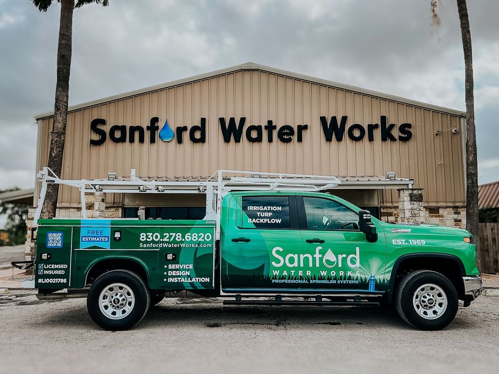 Green Sanford Water Works truck parked in front of a building with the company name on it.