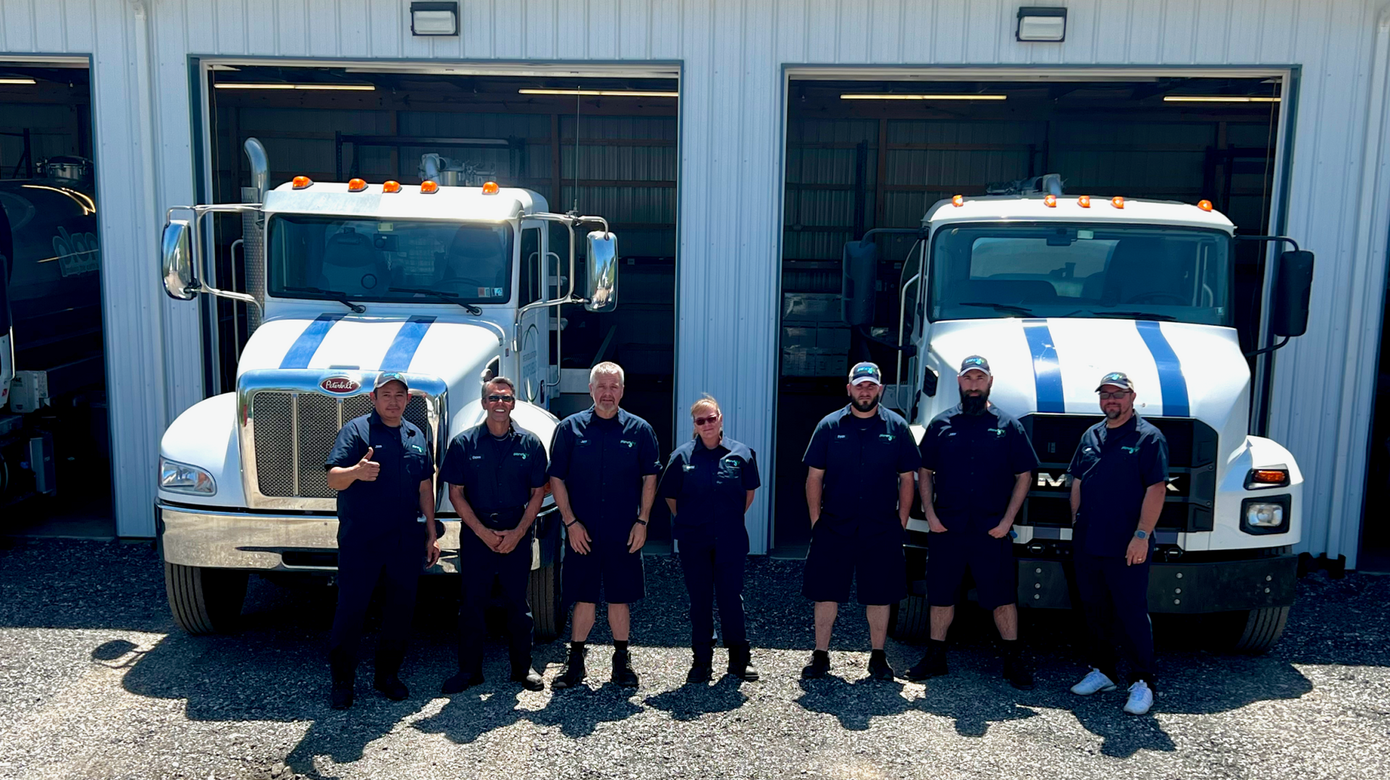 A group of men are standing in front of two trucks.