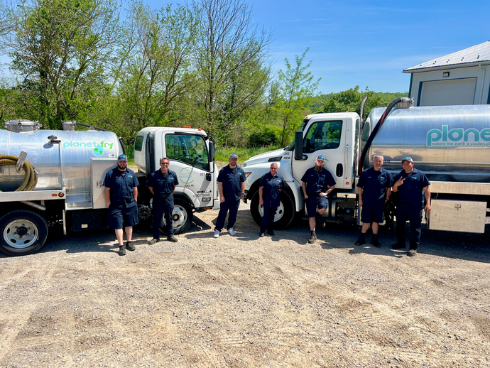 A group of men are standing in front of a row of trucks.