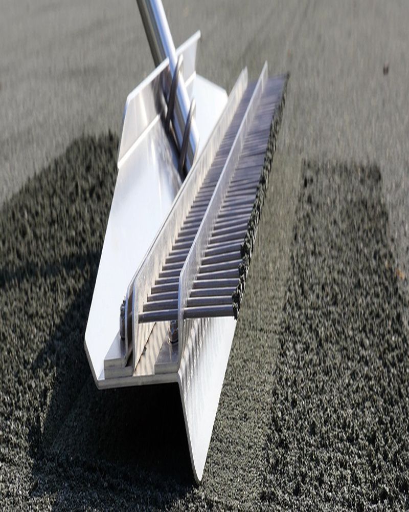A metal rake is sitting on top of a pile of gravel