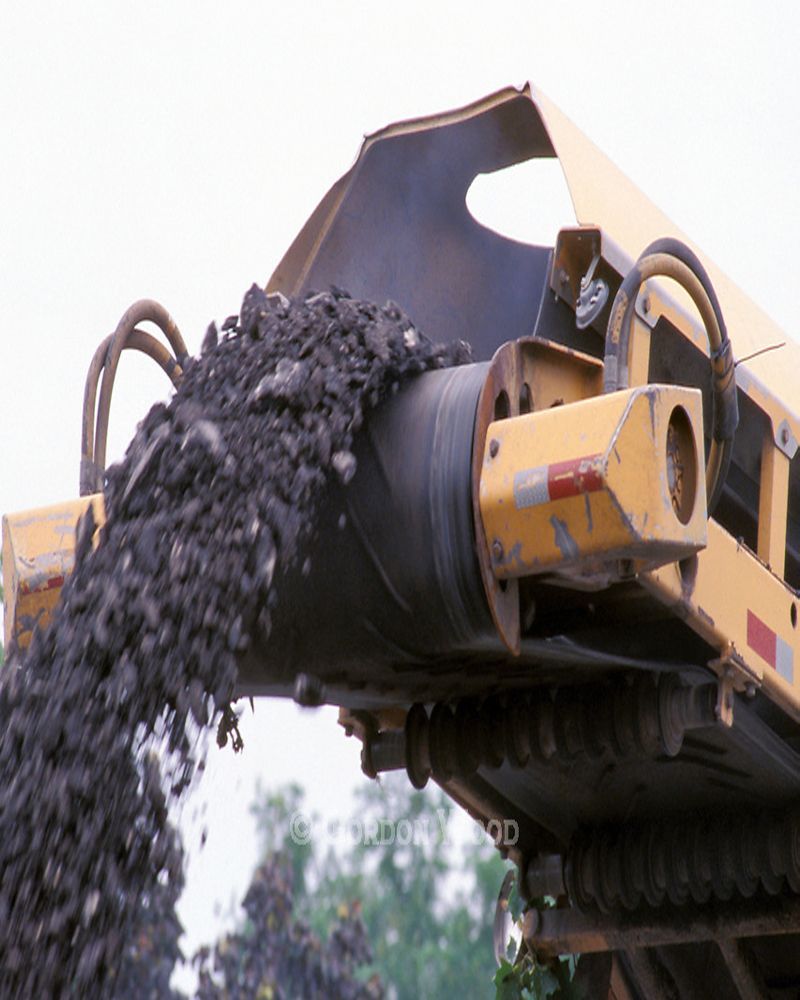 A yellow truck is pouring coal into a conveyor belt