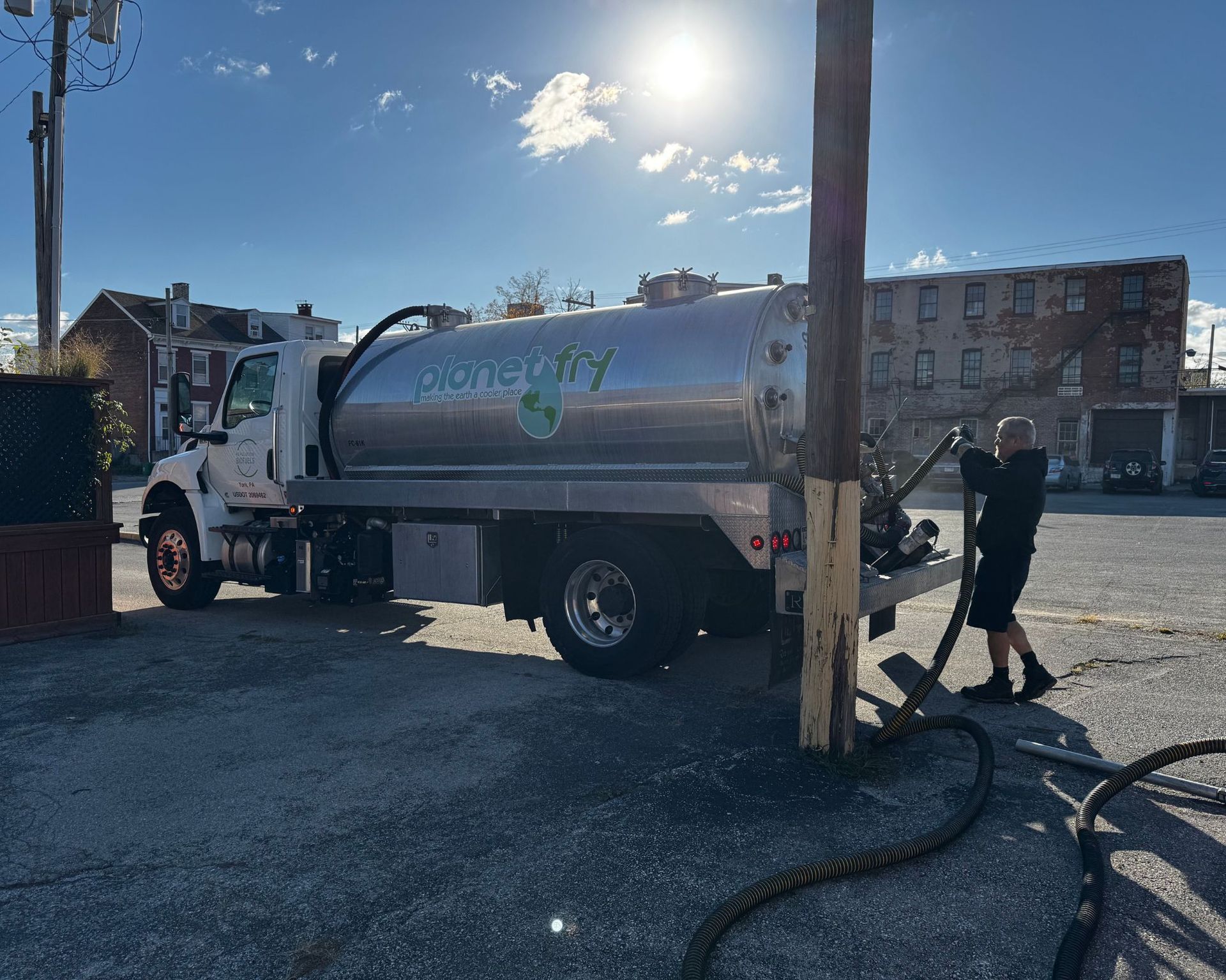 A man is standing next to a vacuum truck in a parking lot.