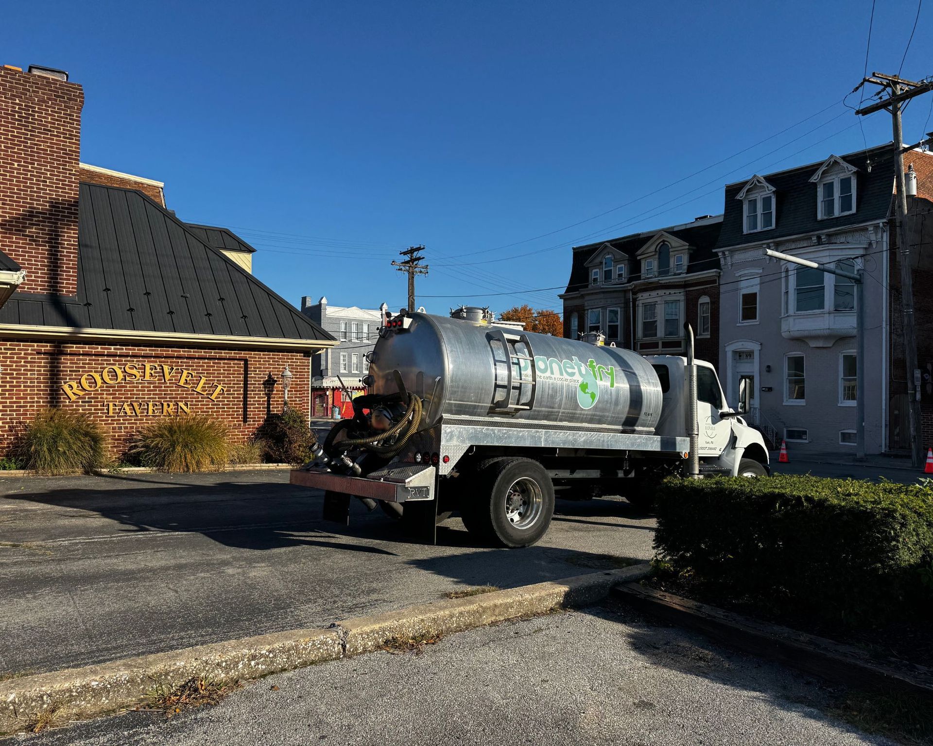 A vacuum truck is parked in front of a brick building.