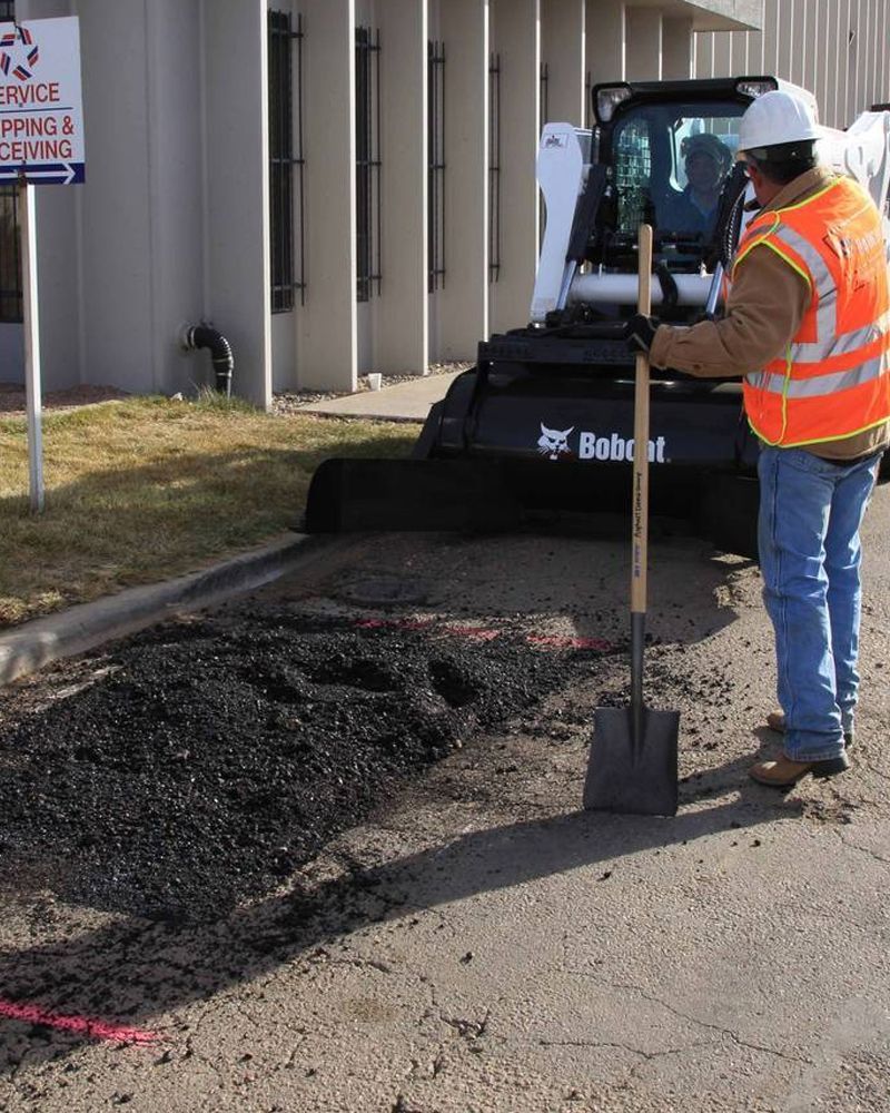A man with a shovel in front of a bobcat machine