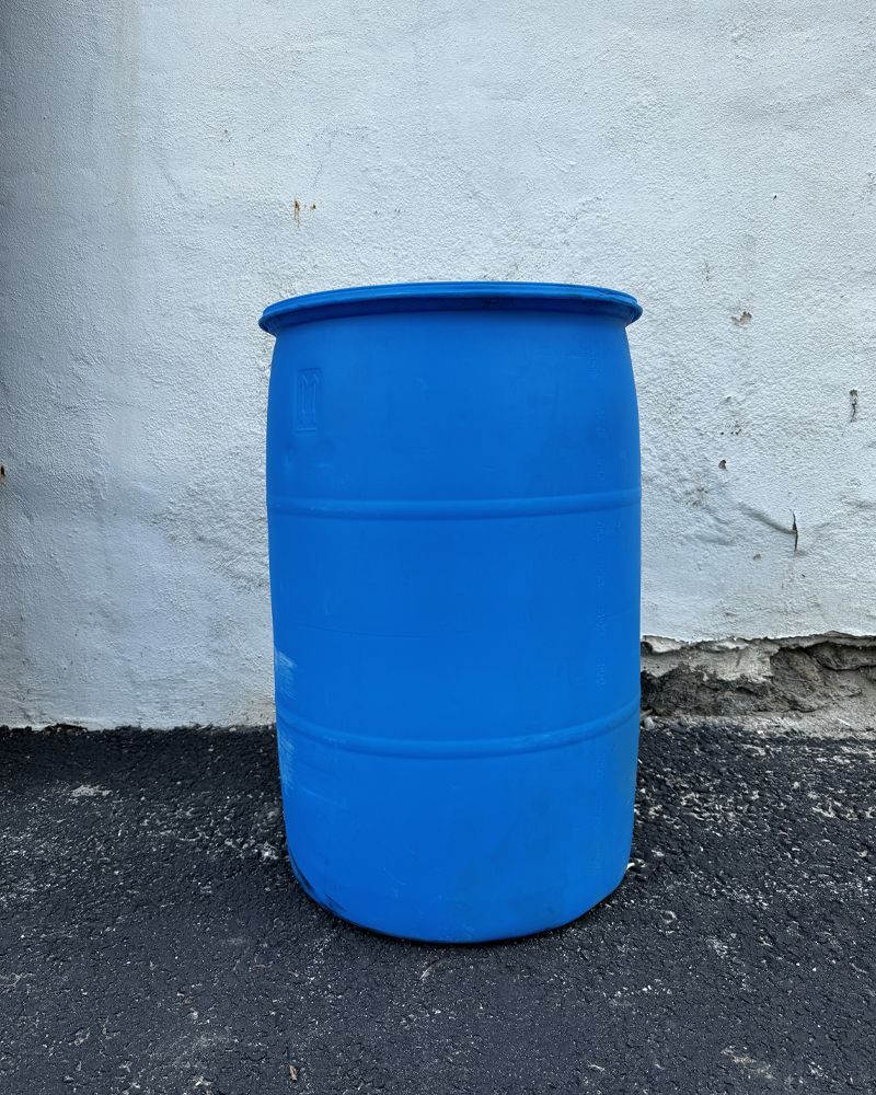 A blue plastic barrel is sitting in front of a white wall