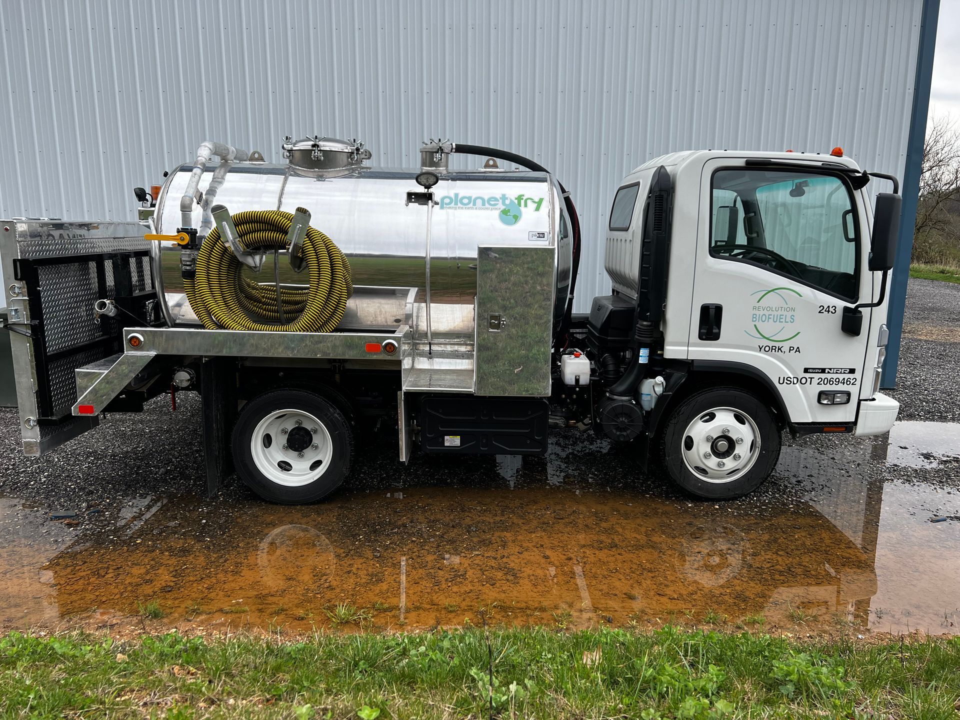 A white vacuum truck is parked in front of a building.