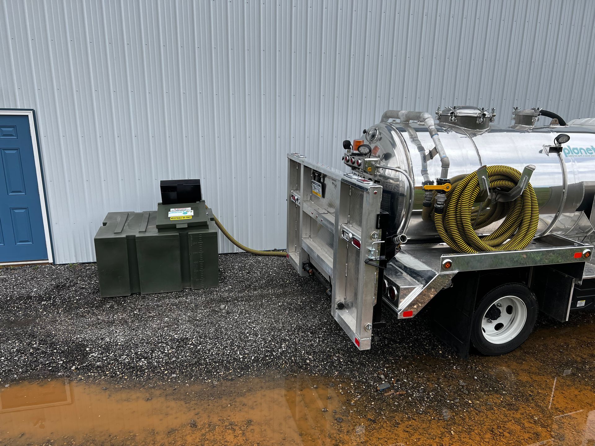 A vacuum truck with a hose attached to it is parked in front of a building.