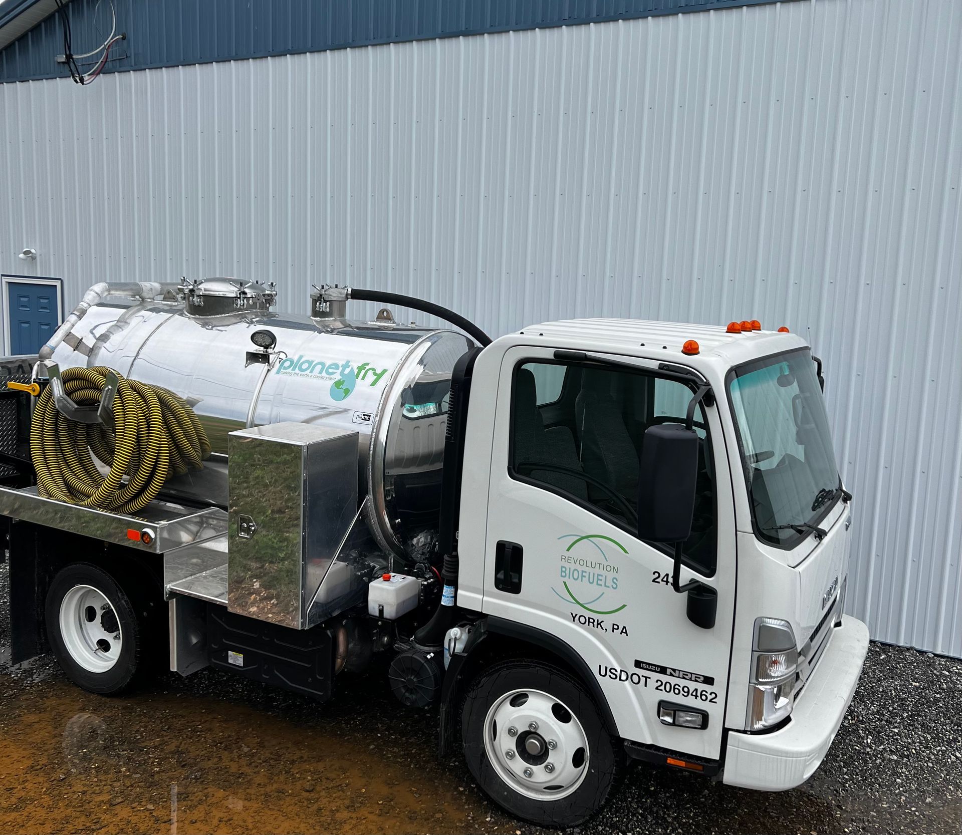 A white vacuum truck is parked in front of a building.