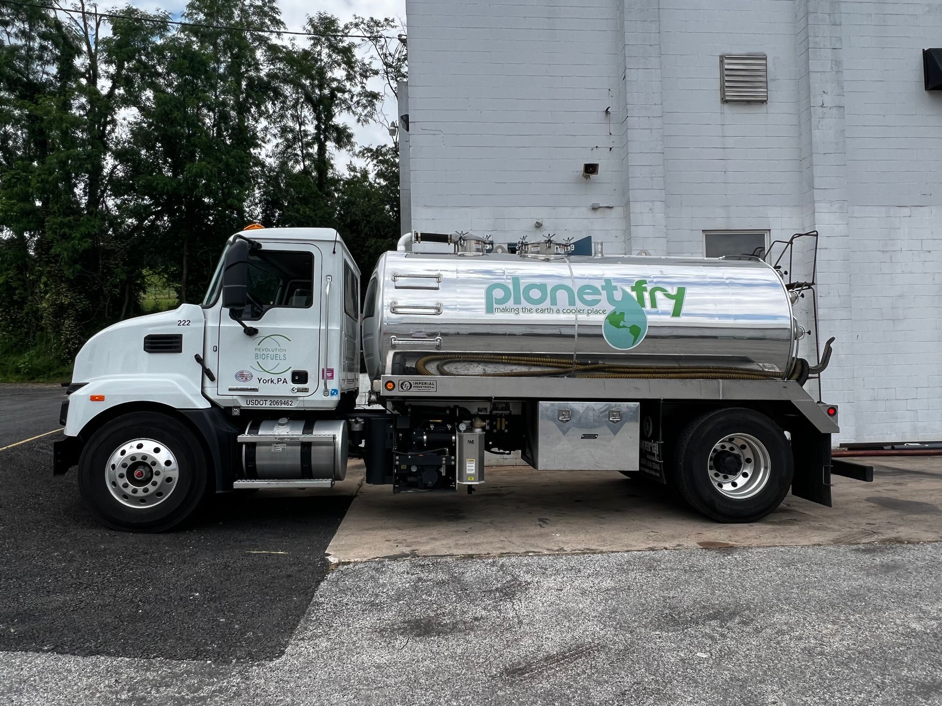 A white truck with planet fry written on the side is parked in front of a building.