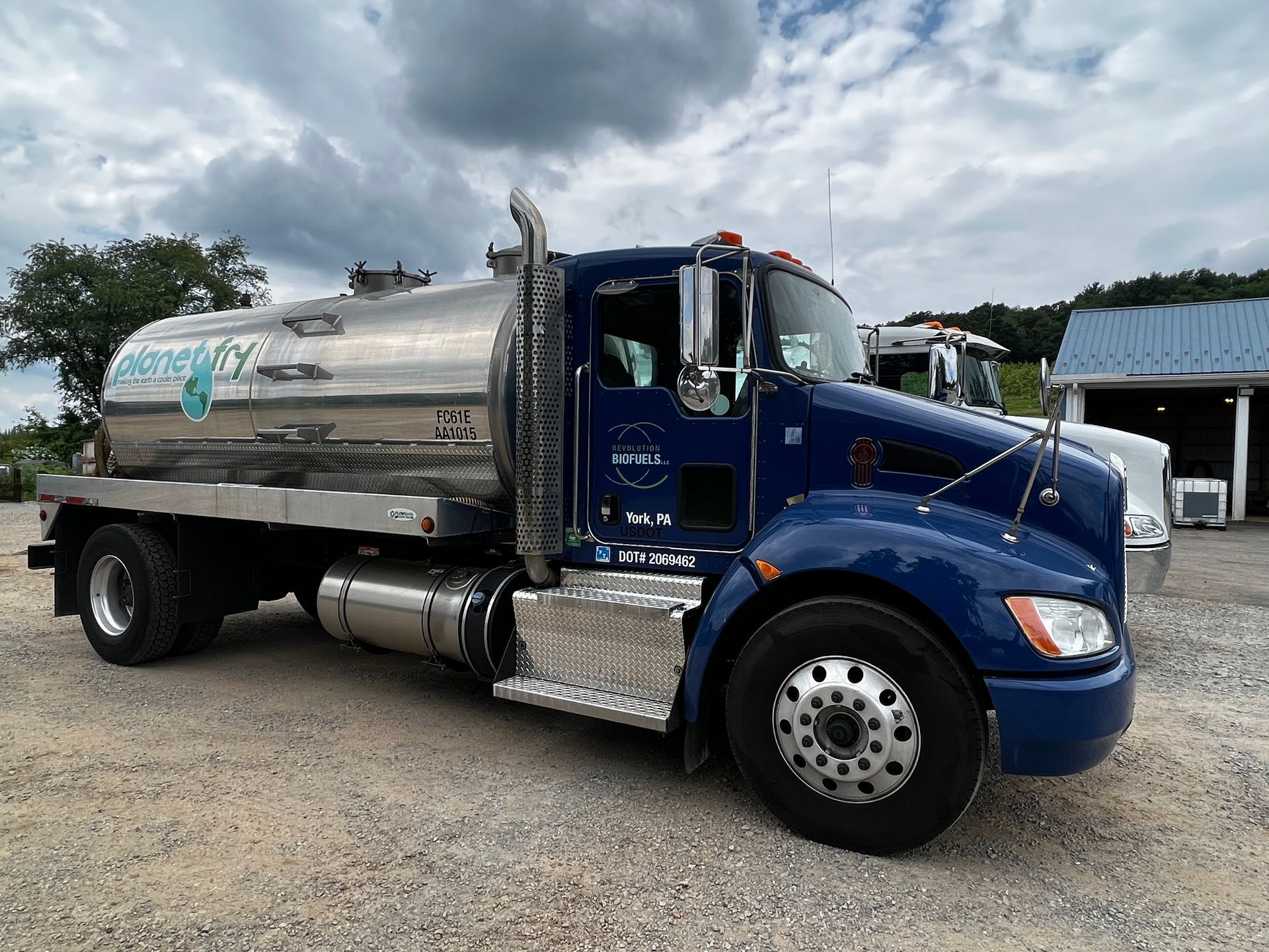 A blue and silver semi truck is parked in a gravel lot.