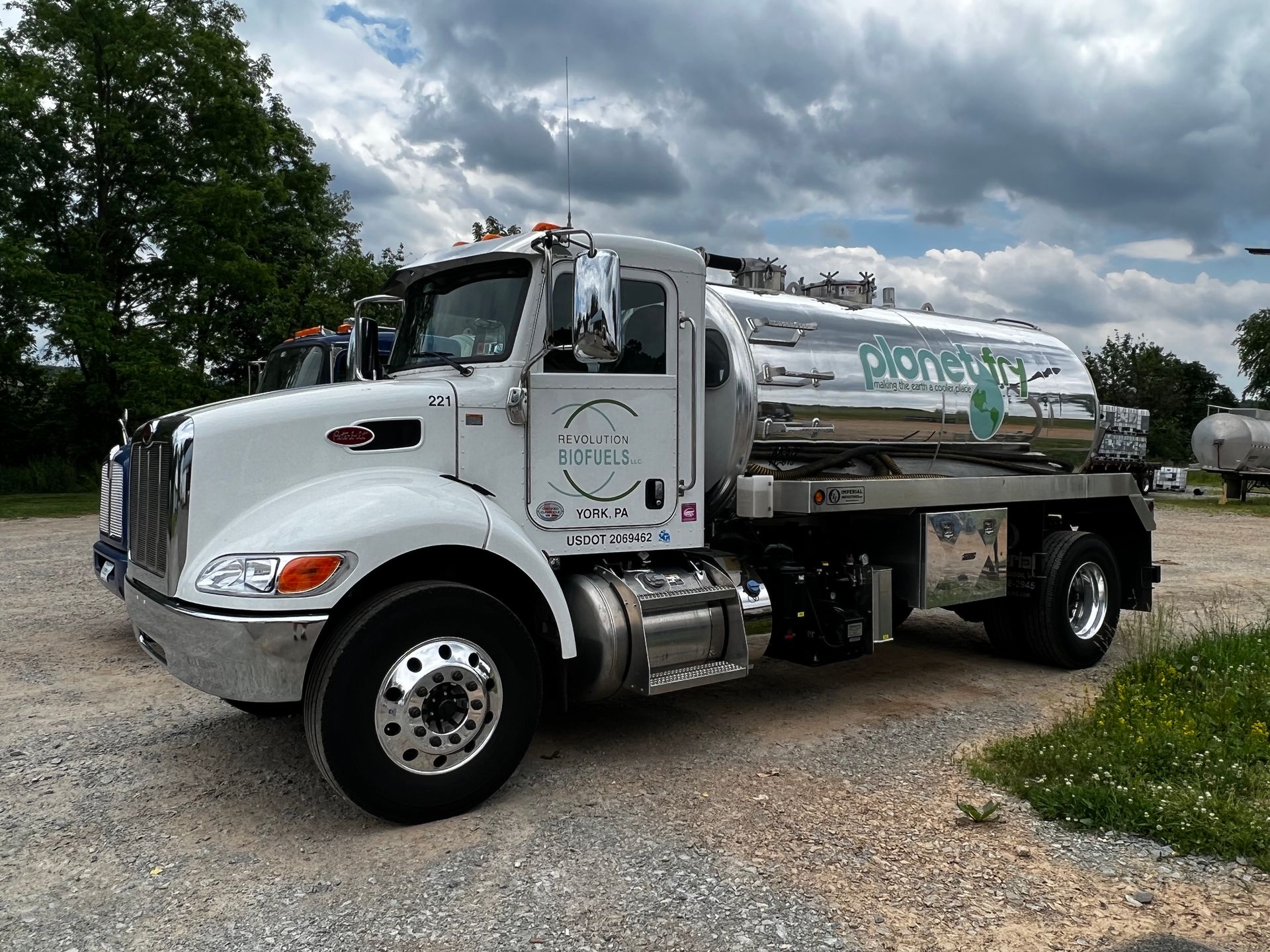 A white tanker truck is parked in a gravel lot.