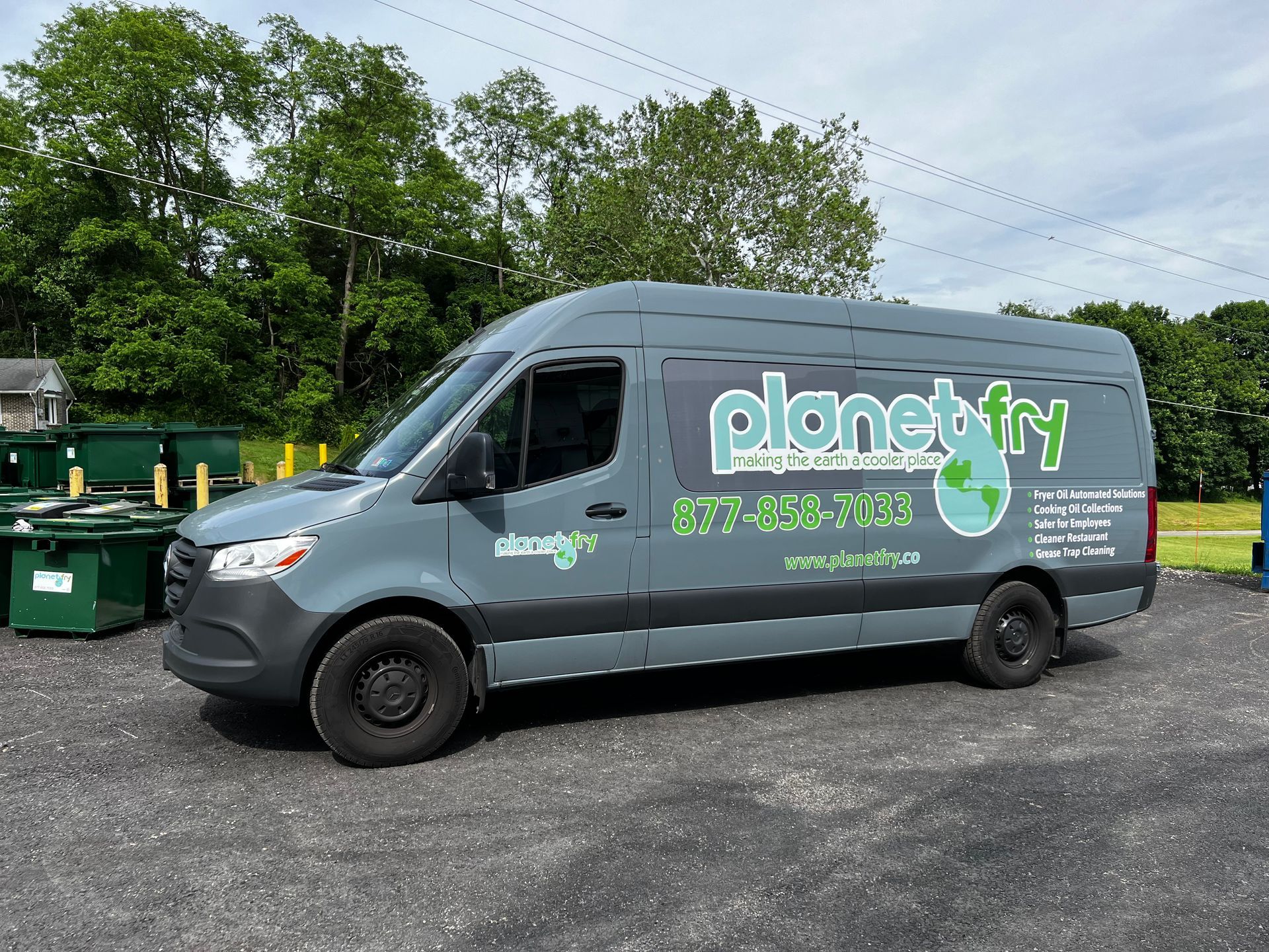 A gray van with the word planet dry on the side is parked in a parking lot.